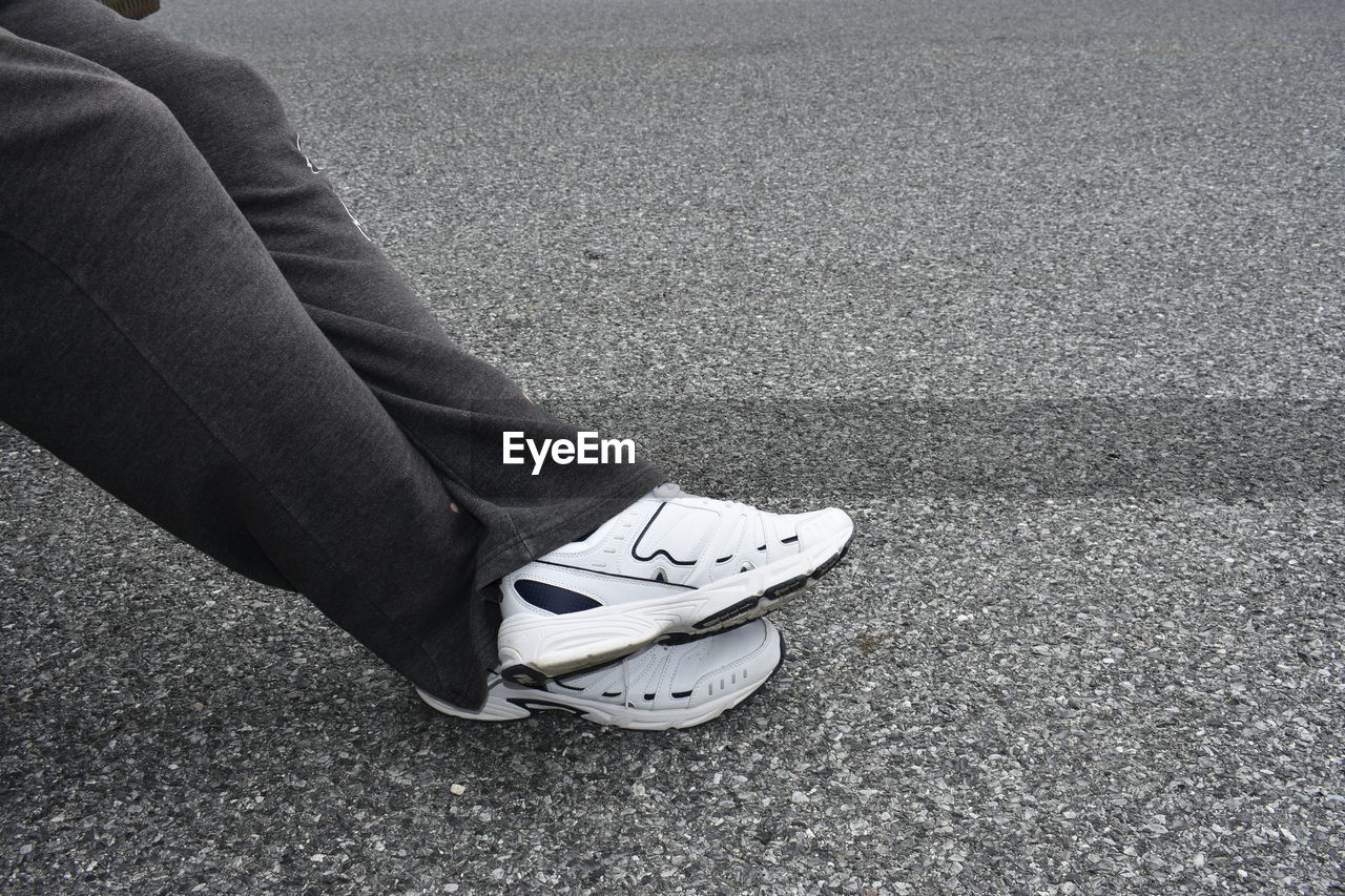 LOW SECTION OF WOMAN STANDING ON ASPHALT