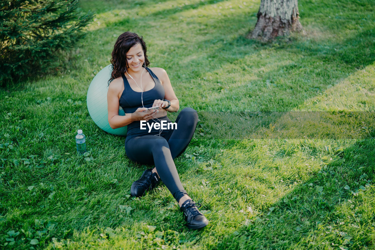 High angle view of woman using smart phone while sitting on land