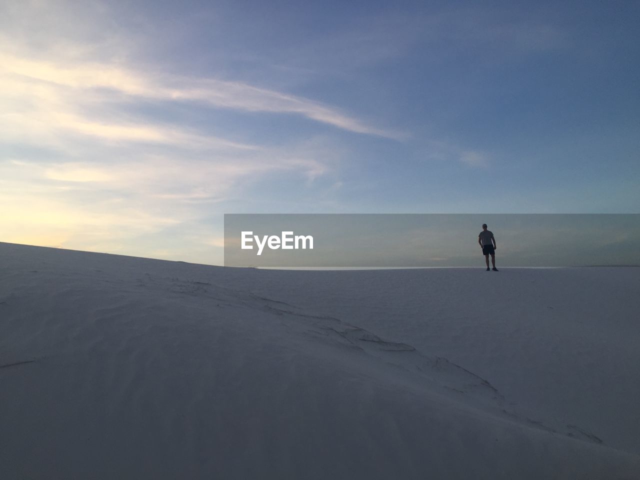 MAN STANDING ON SAND DUNE