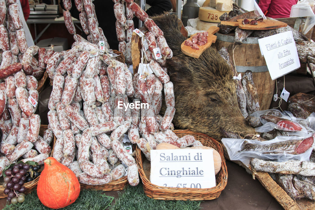 Salami for sale by dead wild boar at market