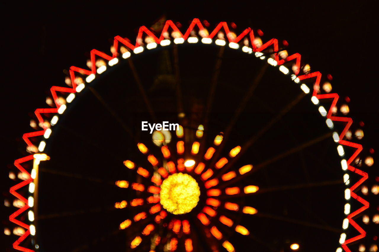 Blurred motion of illuminated ferris wheel against sky at night