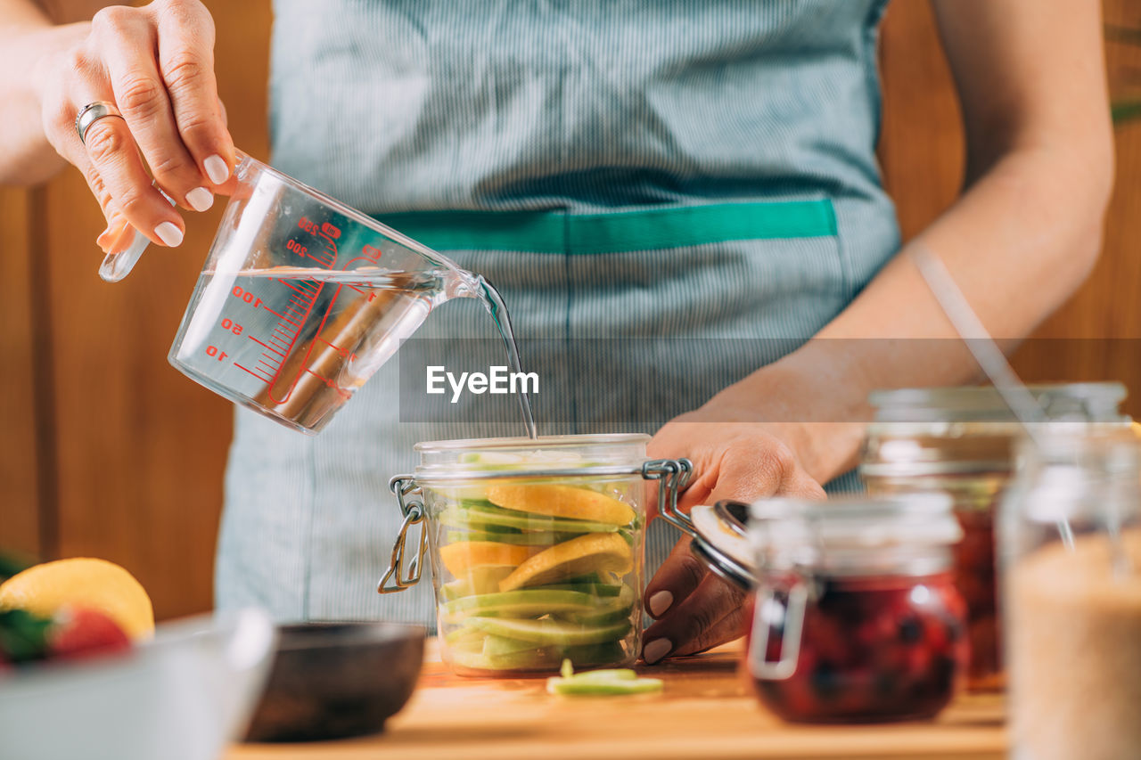 MIDSECTION OF WOMAN HOLDING DRINK IN JAR