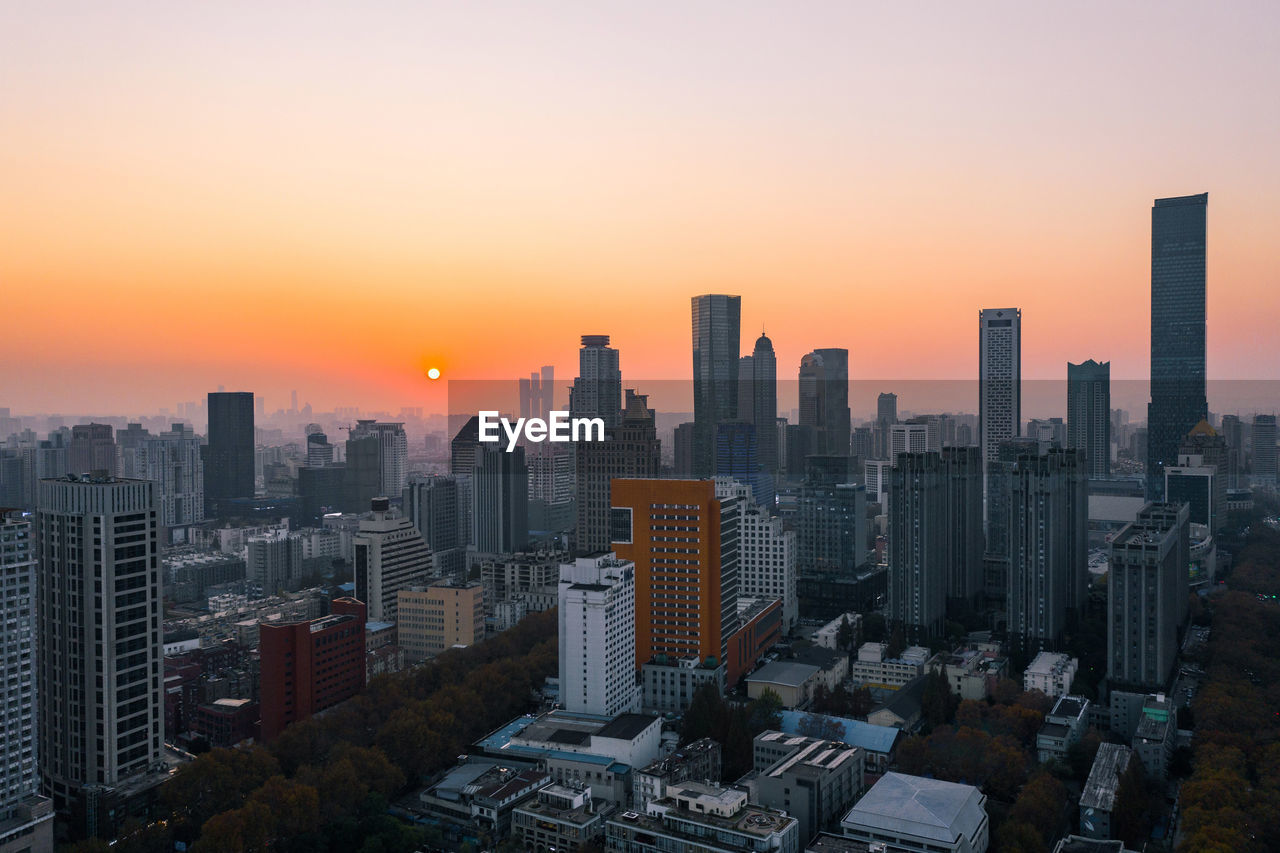 AERIAL VIEW OF BUILDINGS IN CITY AGAINST ROMANTIC SKY