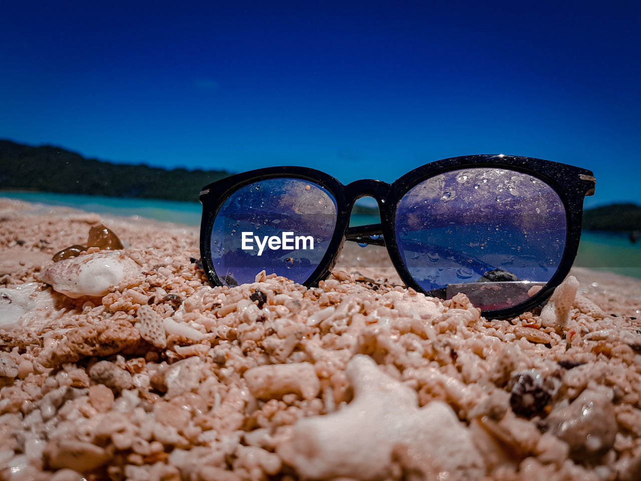 CLOSE-UP OF SUNGLASSES ON BEACH