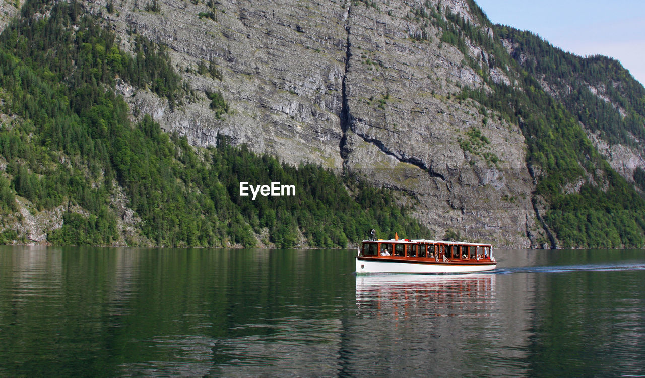 Boat sailing on sea by mountain