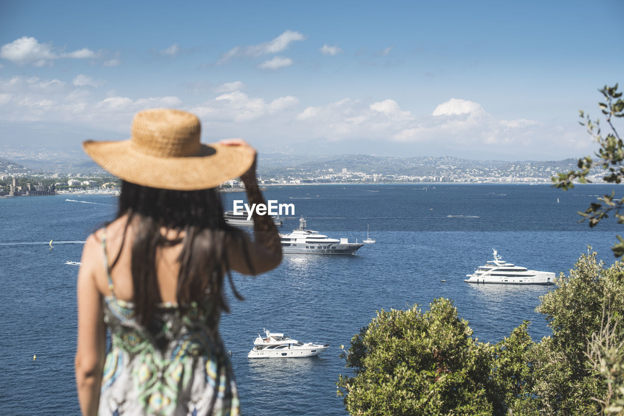 REAR VIEW OF WOMAN LOOKING AT SEA BY BOAT