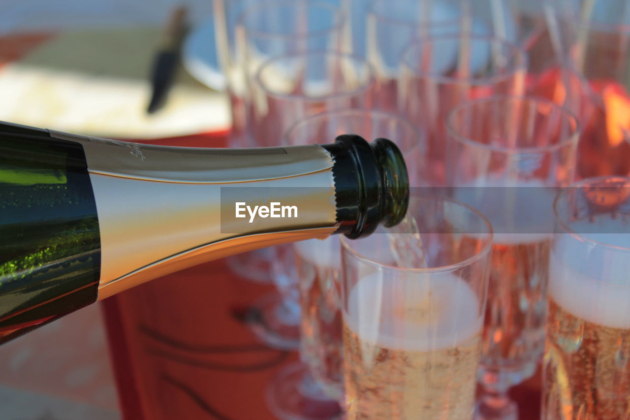 Close-up of champagne pouring from bottle in glass 