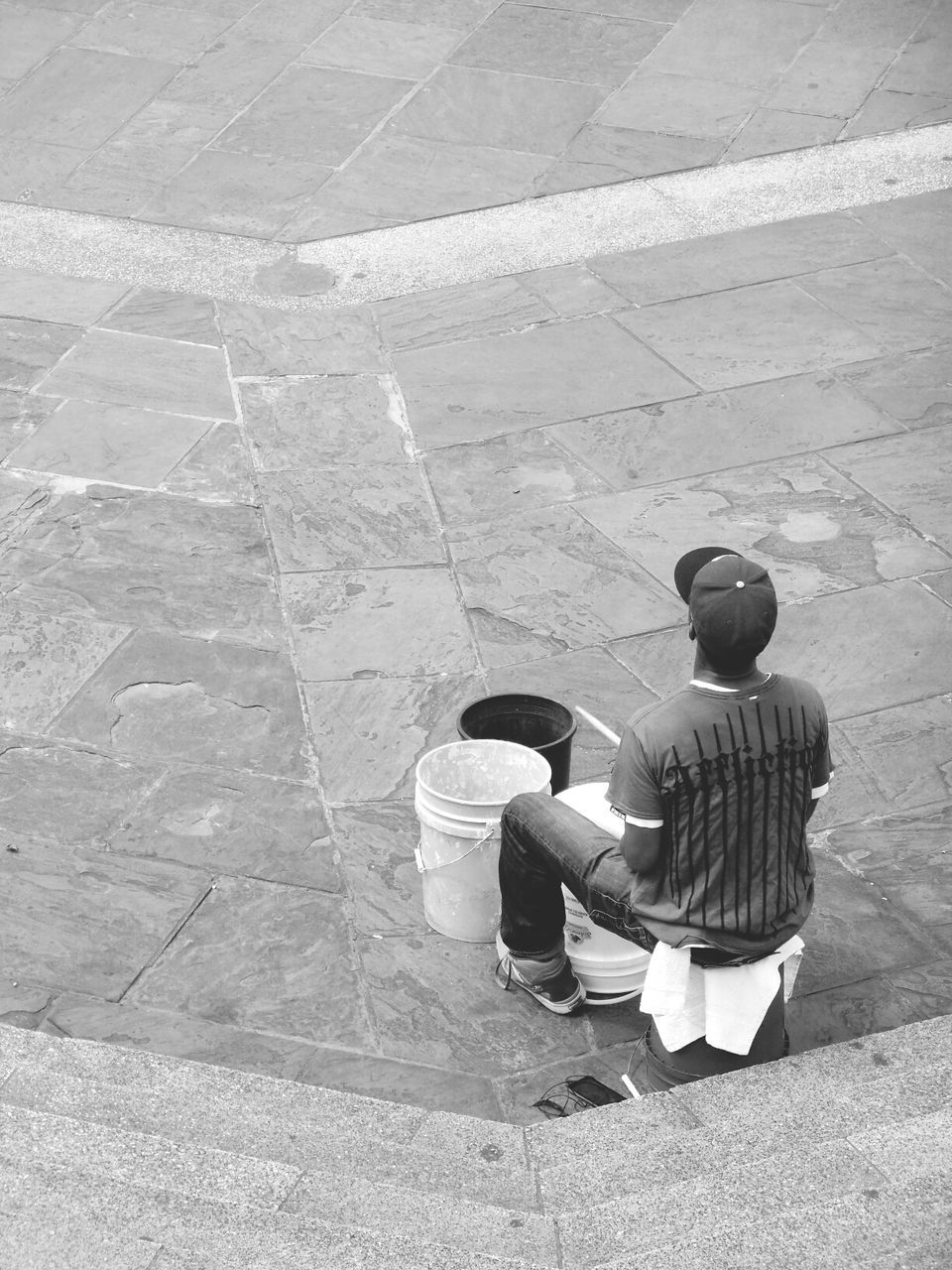 Rear view of a man sitting with buckets on road