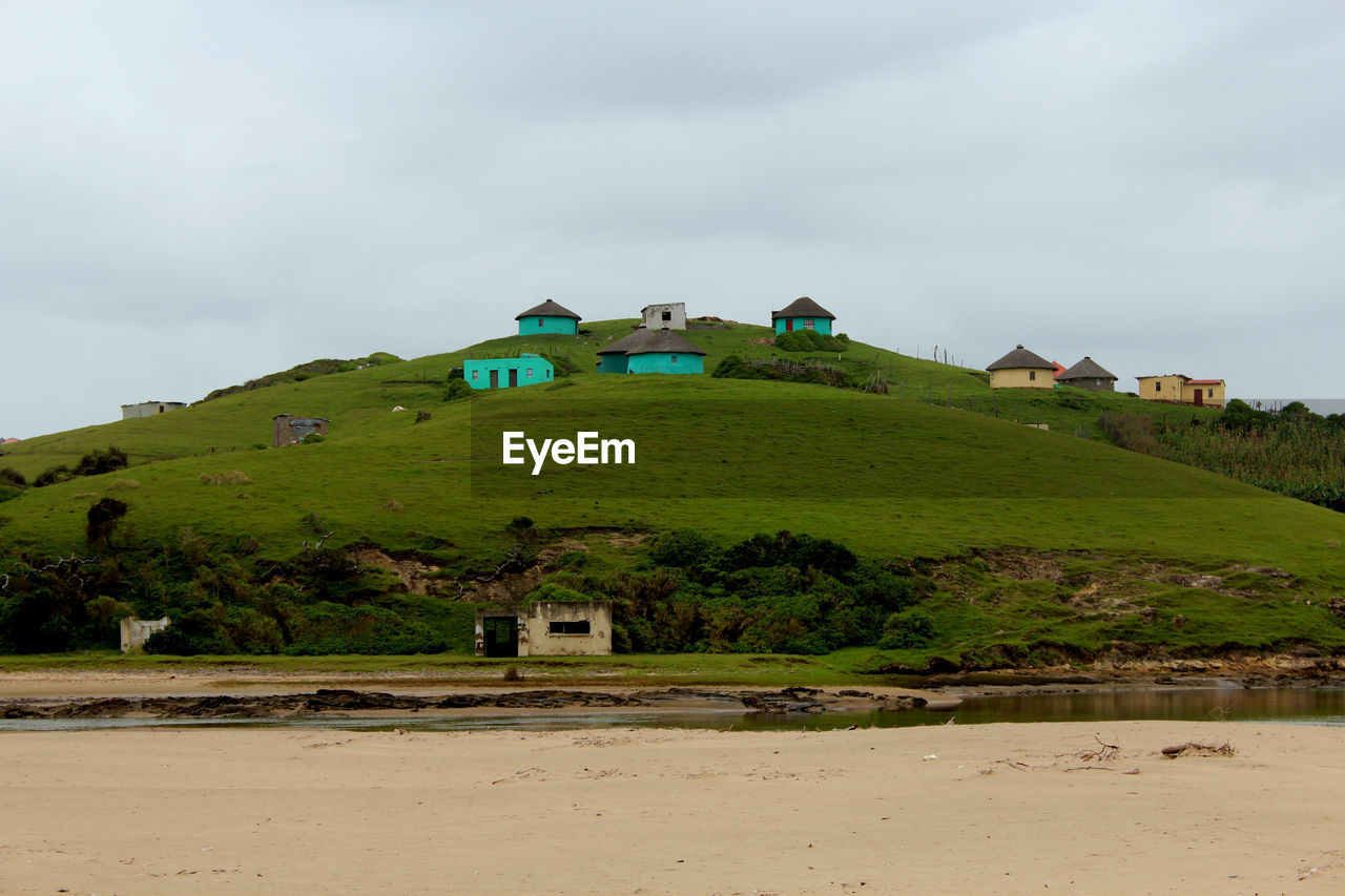 Low angle view of houses on mountain against cloudy sky