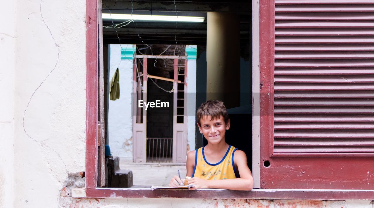 PORTRAIT OF BOY SITTING ON WINDOW