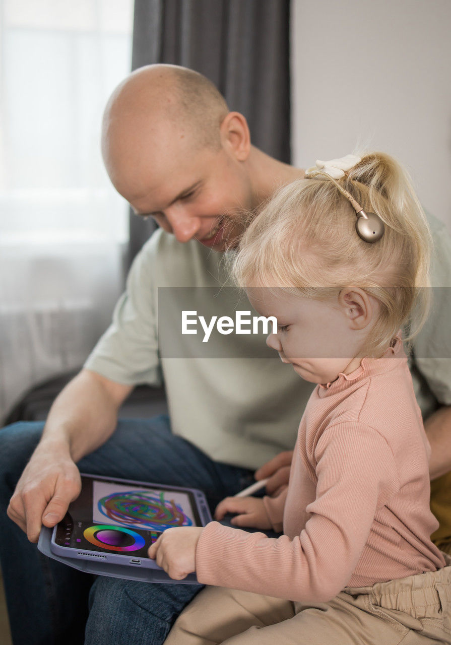 side view of mother and daughter sitting on sofa at home