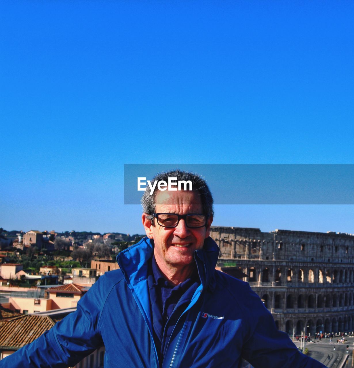 Portrait of mature man standing against blue sky