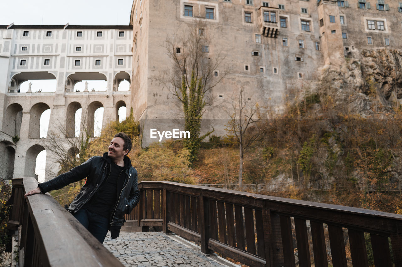 Smiling man standing by railing against building