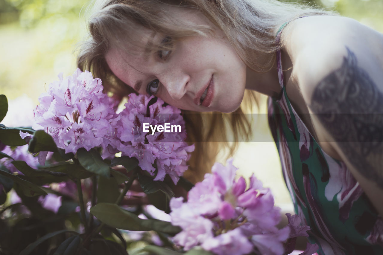 Close up woman bending head over pink flowering shrub portrait picture