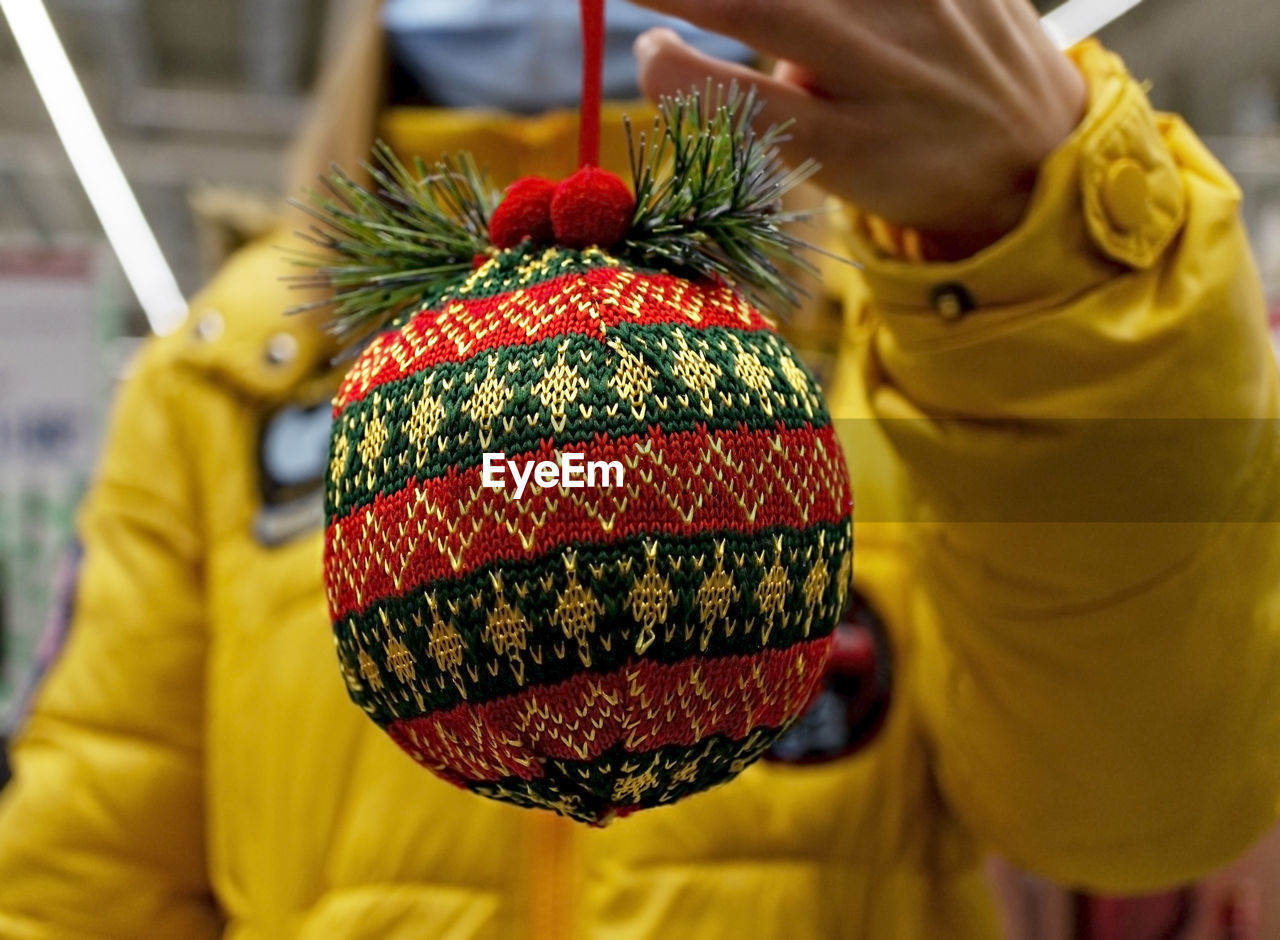 Red green knitted christmas ball in female hand close-up. christmas and new year gift