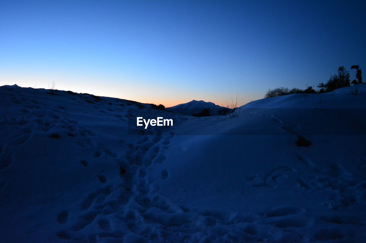 SCENIC VIEW OF SNOW COVERED MOUNTAINS AGAINST CLEAR BLUE SKY DURING SUNSET