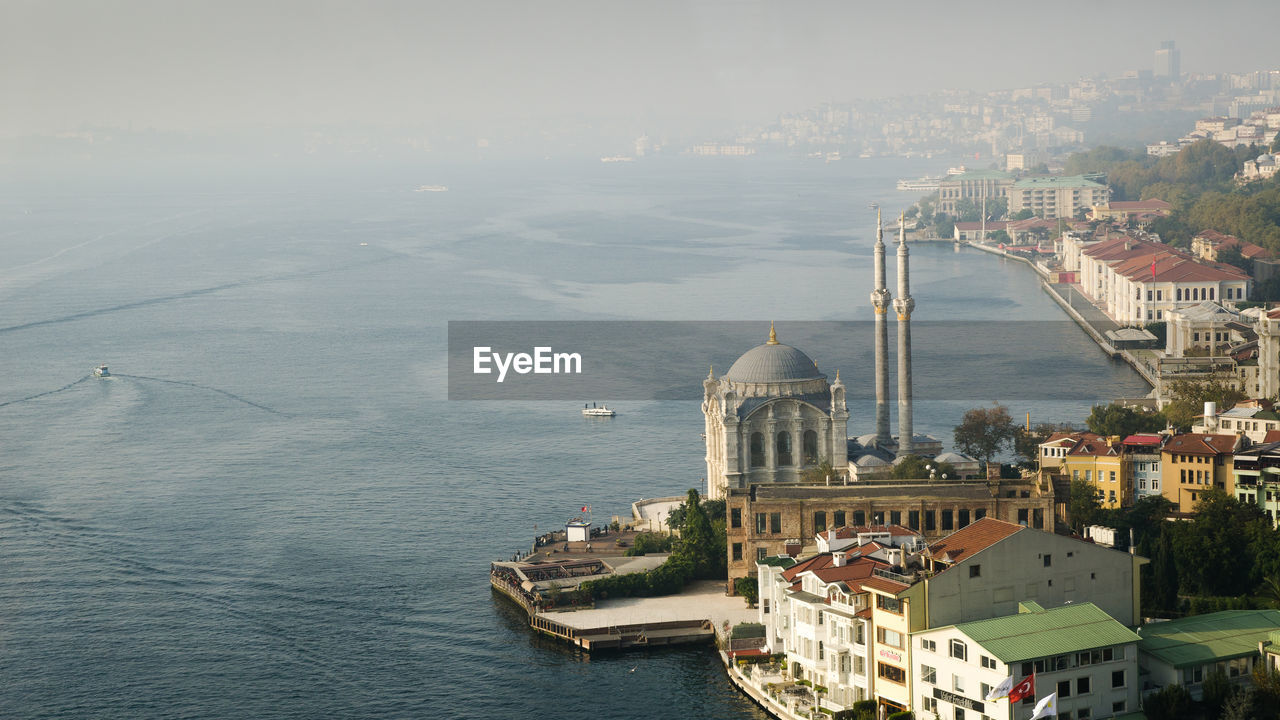 High angle view of cityscape by sea against sky