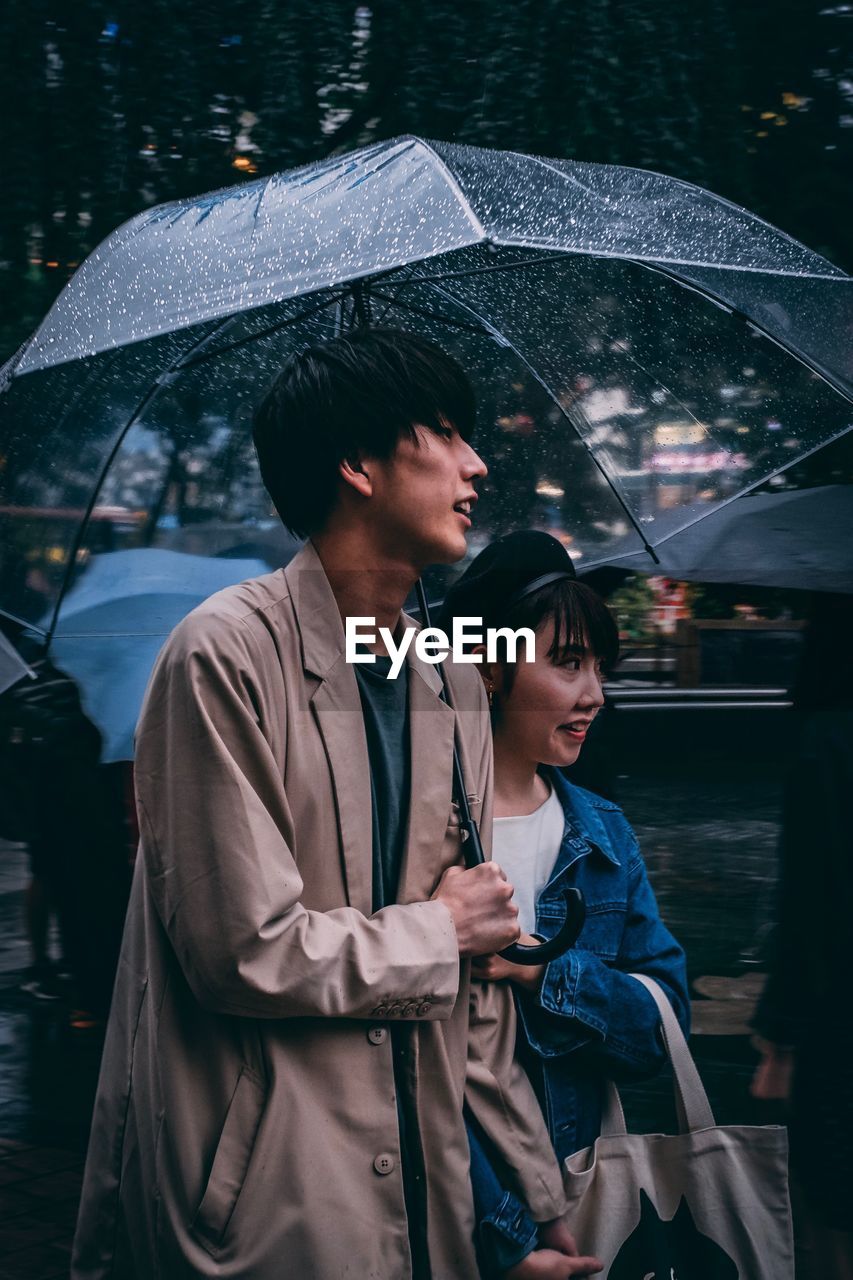 MAN AND WOMAN STANDING AT RAIN