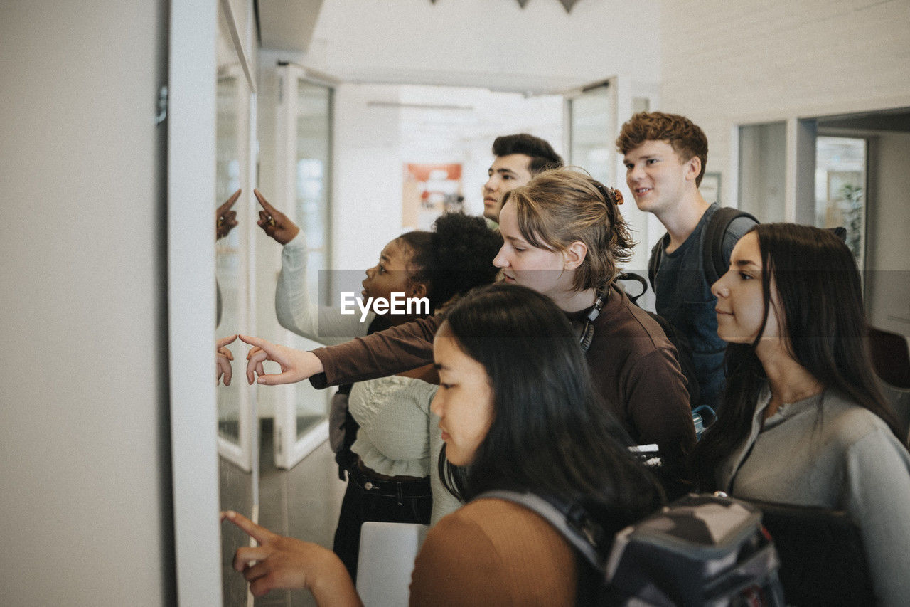 Multiracial students checking result on bulletin board in university