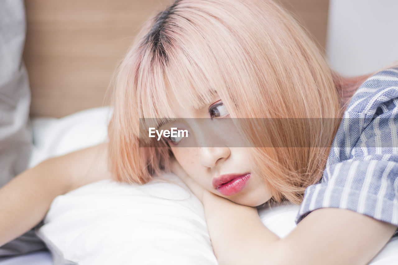 Close-up of thoughtful woman lying on bed