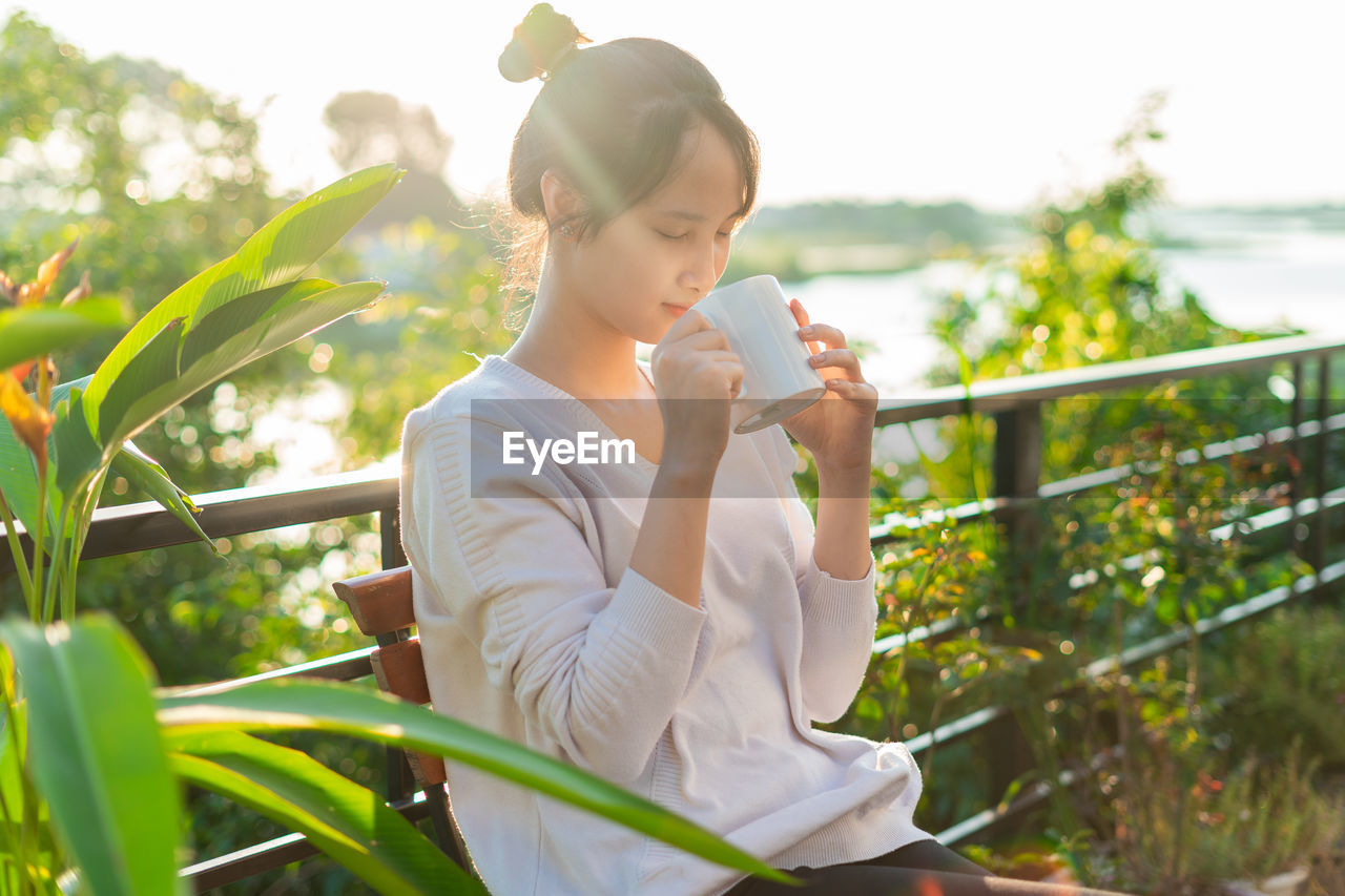 young woman looking away while sitting on field