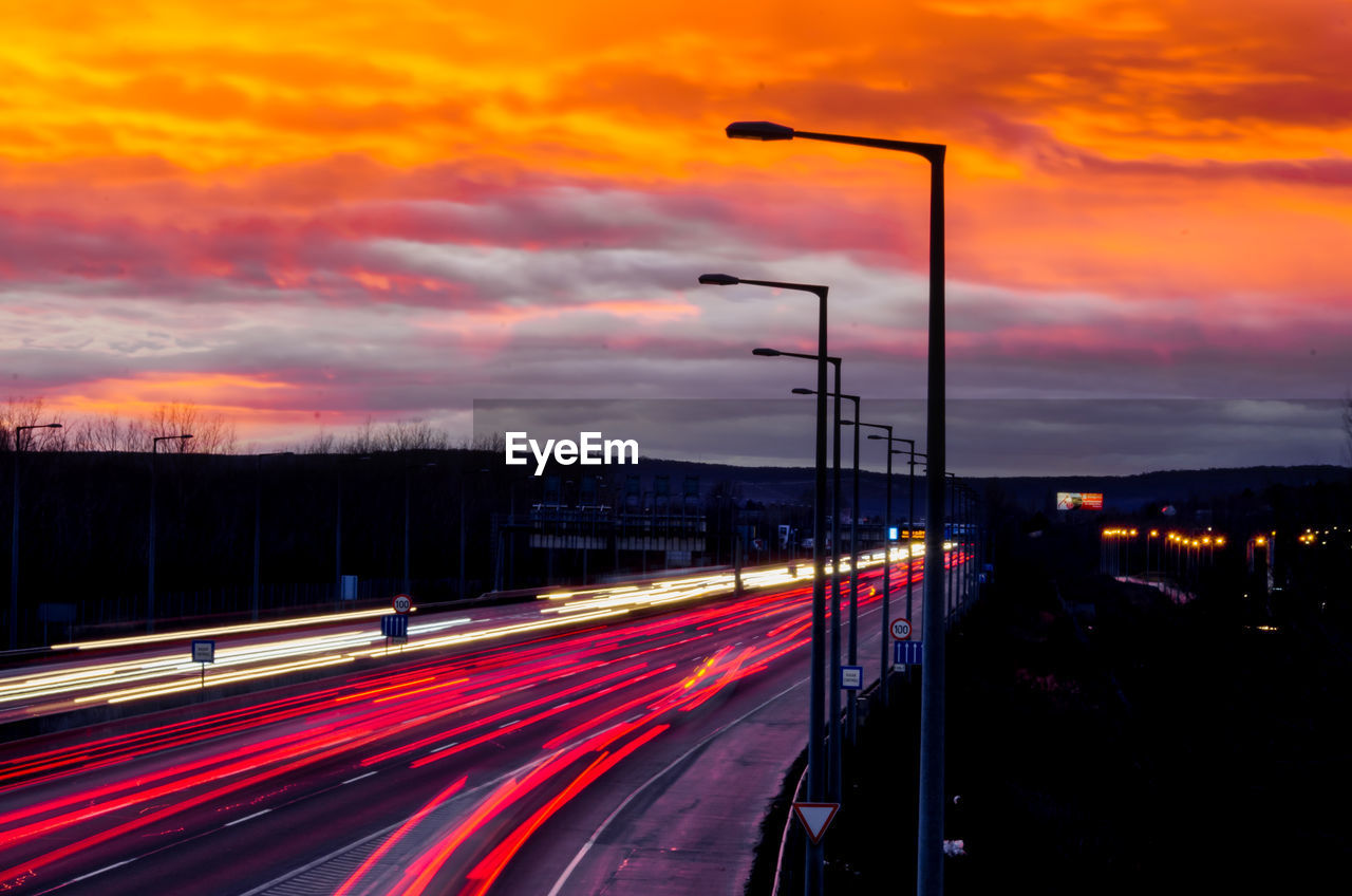 Light trails on road against sky during sunset