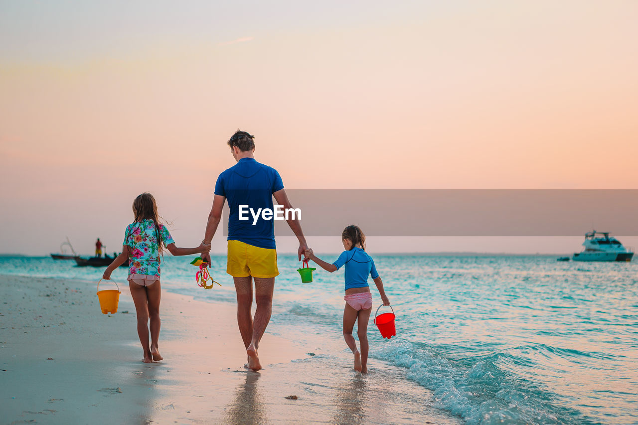 WOMEN ON BEACH AGAINST SKY DURING SUNSET