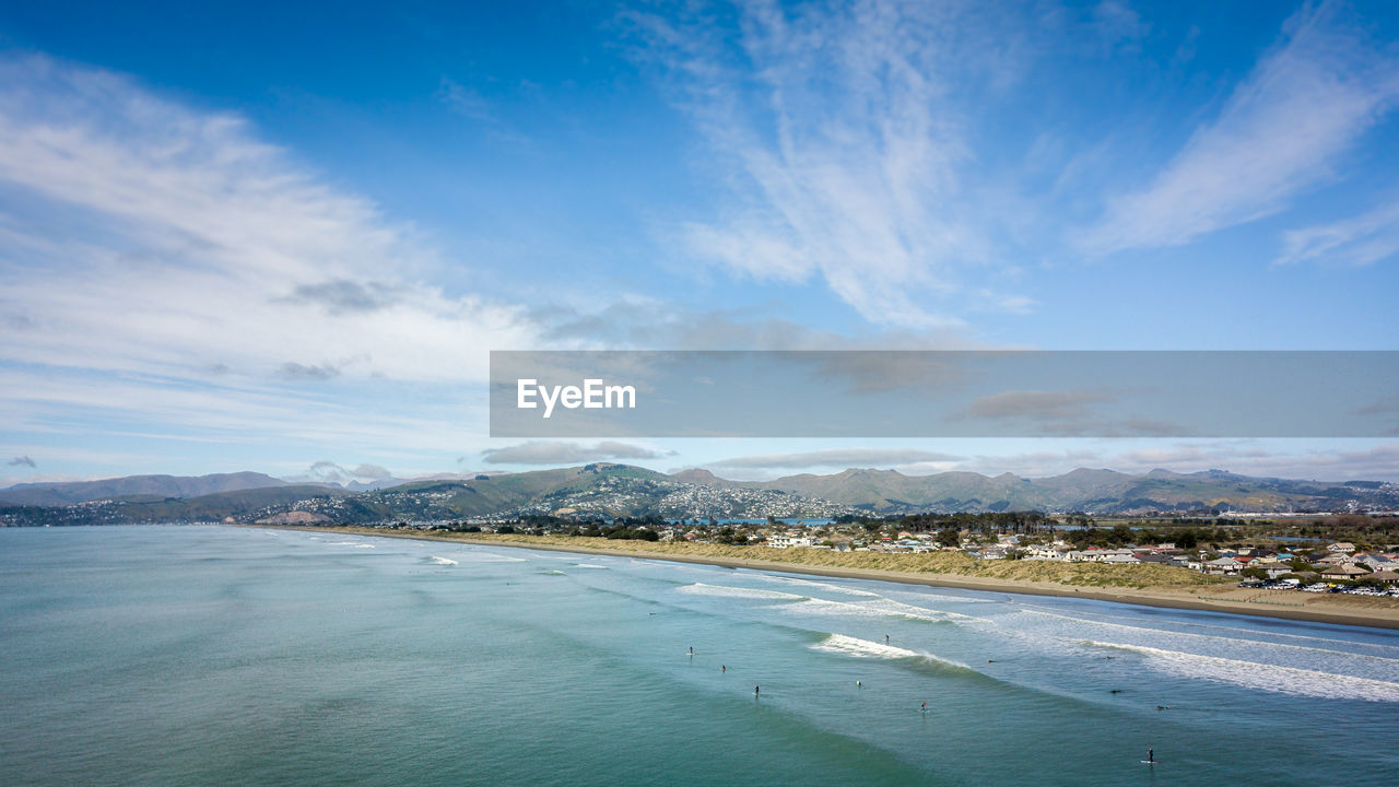 Ocean, beach, surfers and blue sky. aerial shot from new brighton beach in christchurch, new zealand