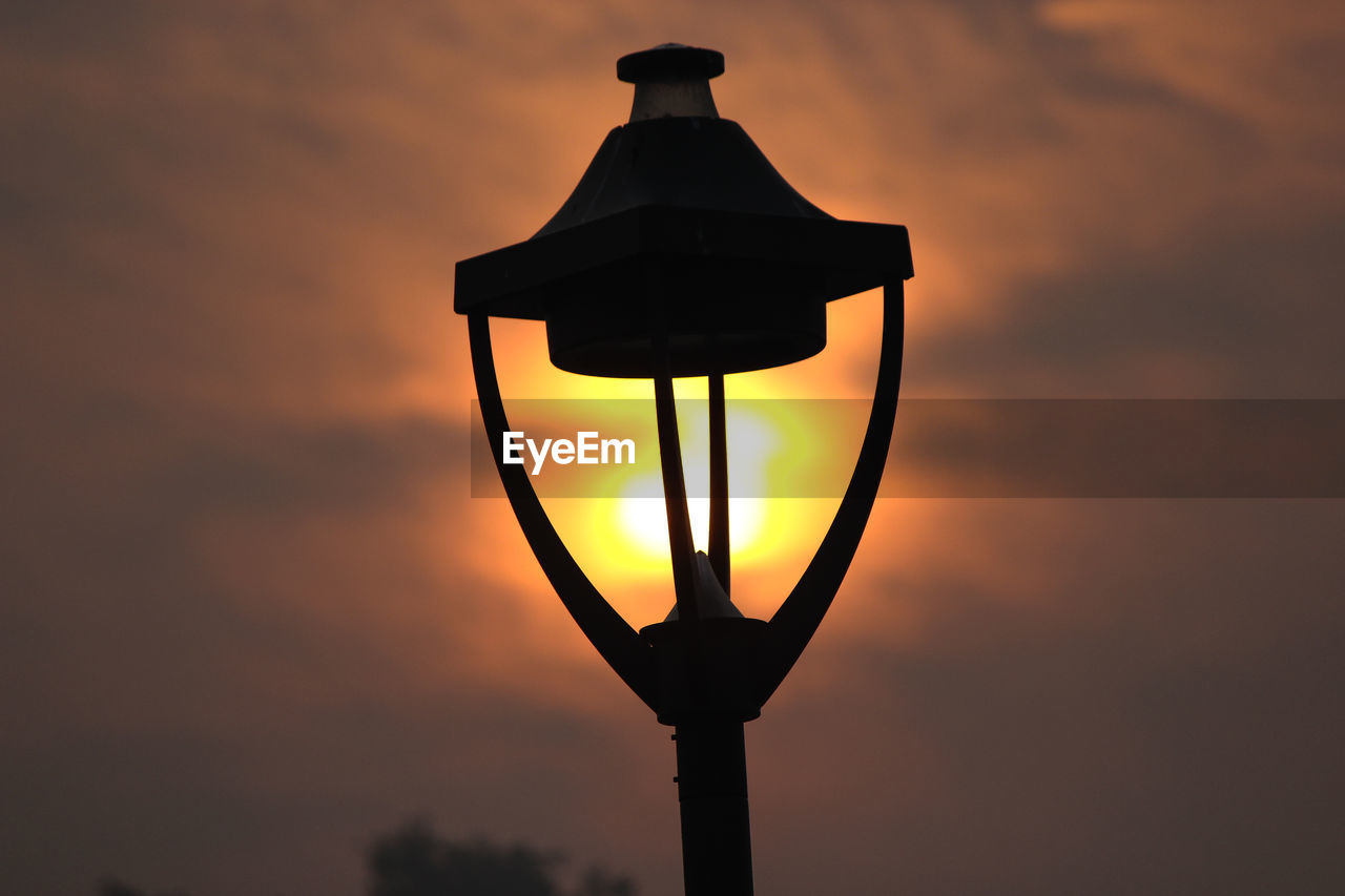 LOW ANGLE VIEW OF STREET LIGHT AGAINST ORANGE SKY