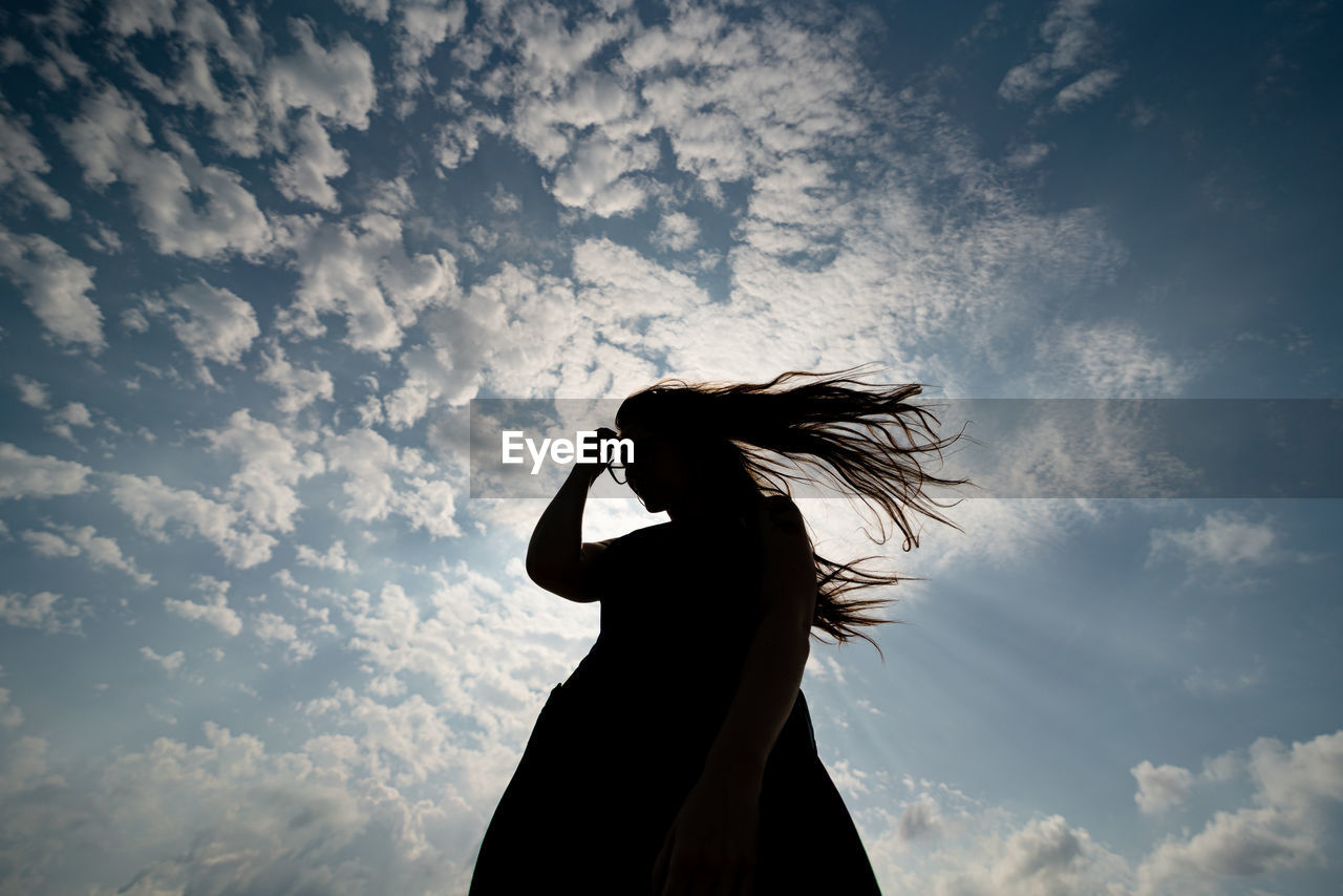 Low angle view of silhouette woman standing against sky