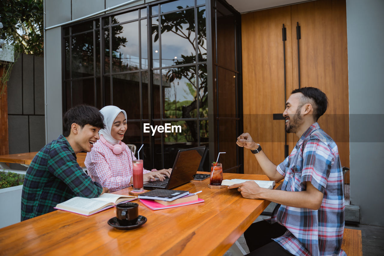 side view of female friends using laptop while sitting in cafe