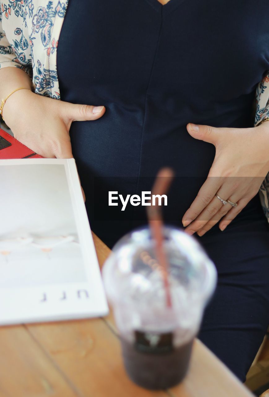 Midsection of pregnant woman touching belly in restaurant