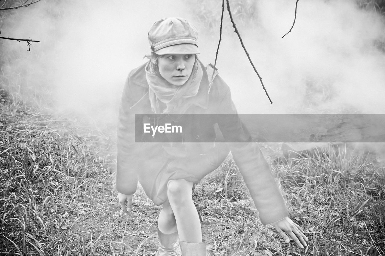 A girl sneaks on the grass in the dense smoke