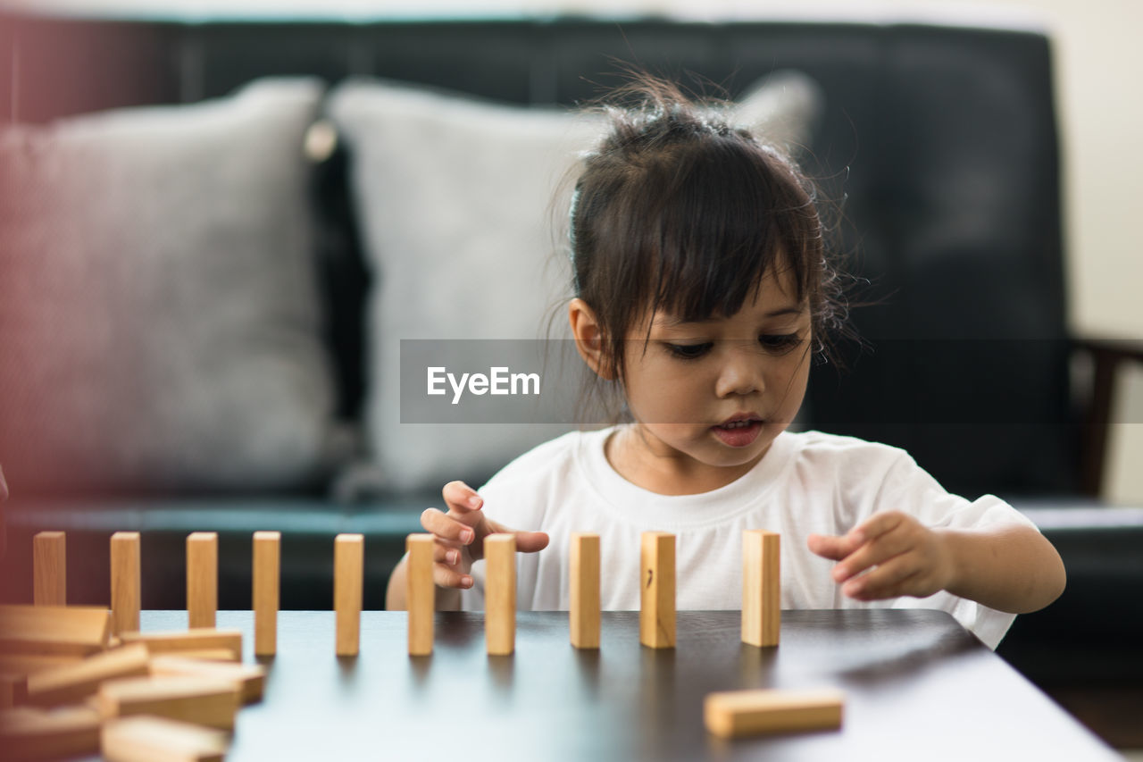 Girl playing with toy blocks on table