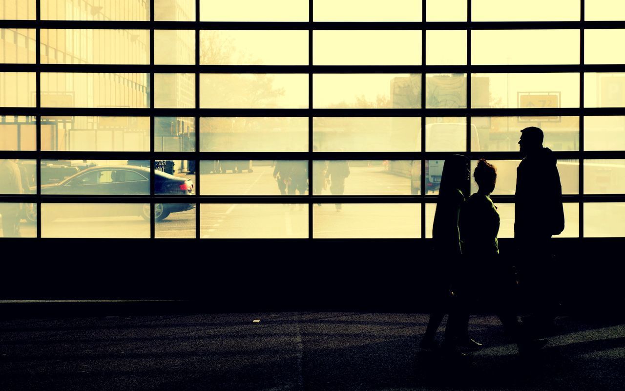 People standing against glass wall