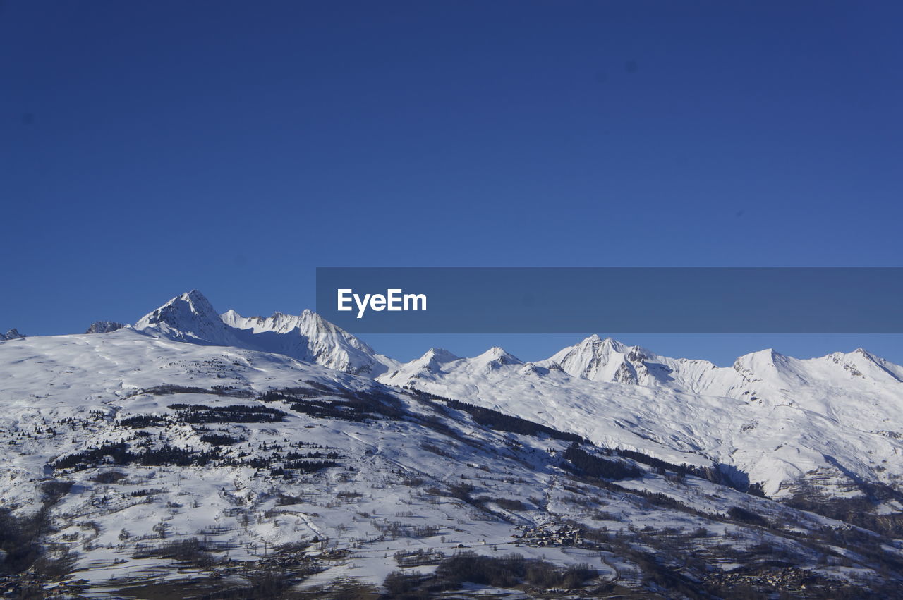 Scenic view of snowcapped mountains against clear blue sky