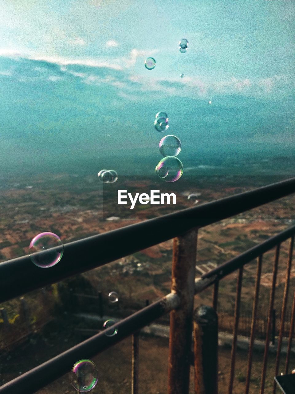 Close-up of bubbles on railing against landscape