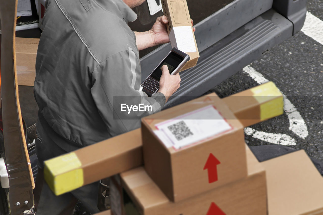 Delivery courier worker with packages boxes with boxcar for delivering in city