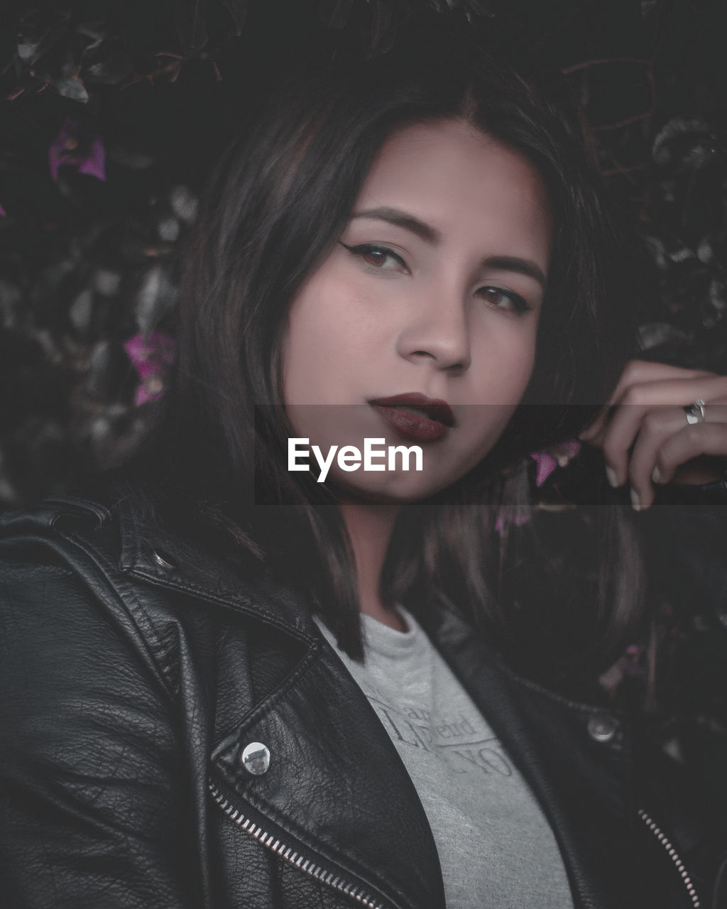 Portrait of beautiful woman against plants in park at night