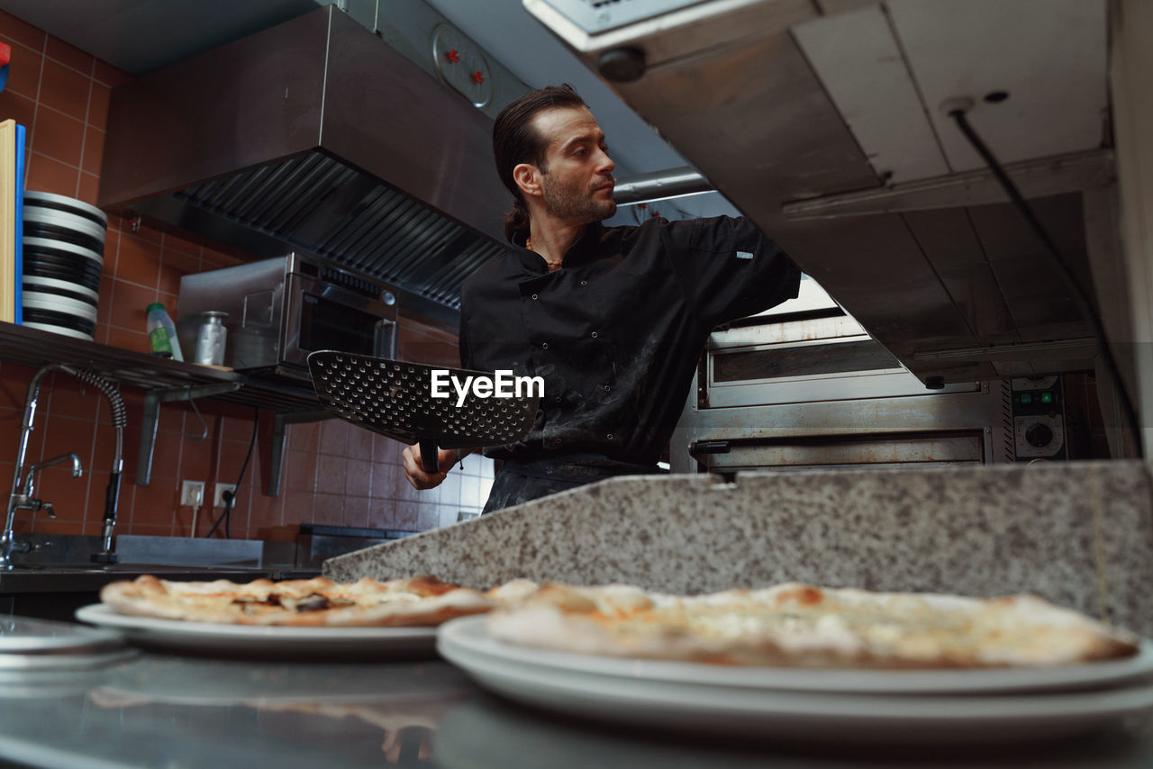 Male chef preparing italian pizza in restaurant kitchen