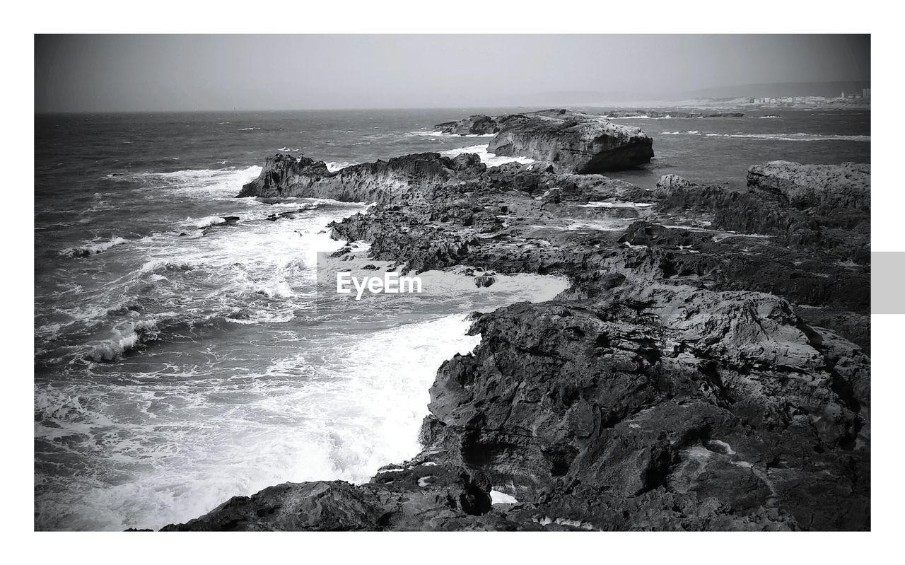 Scenic view of sea by cliff against sky