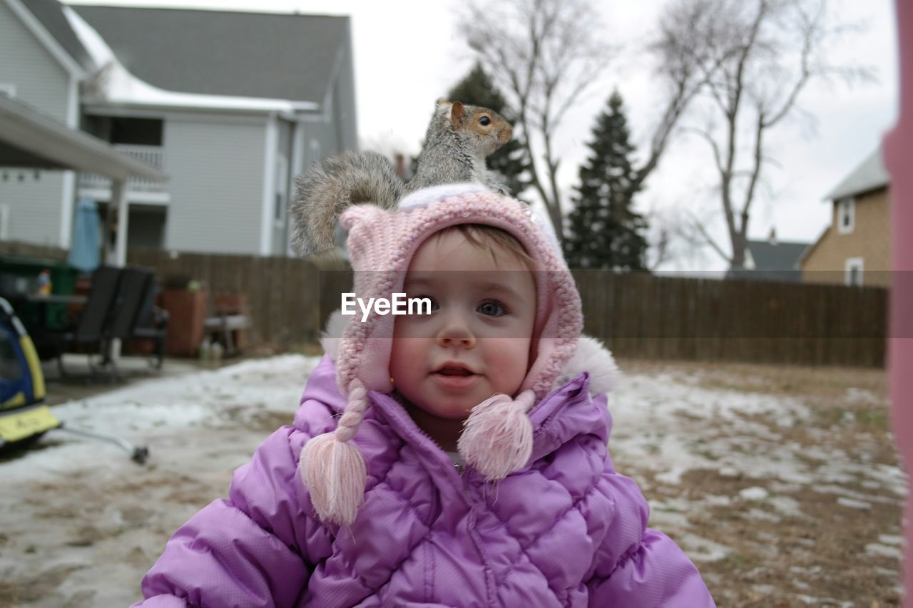 Portrait of cute girl with squirrel on head