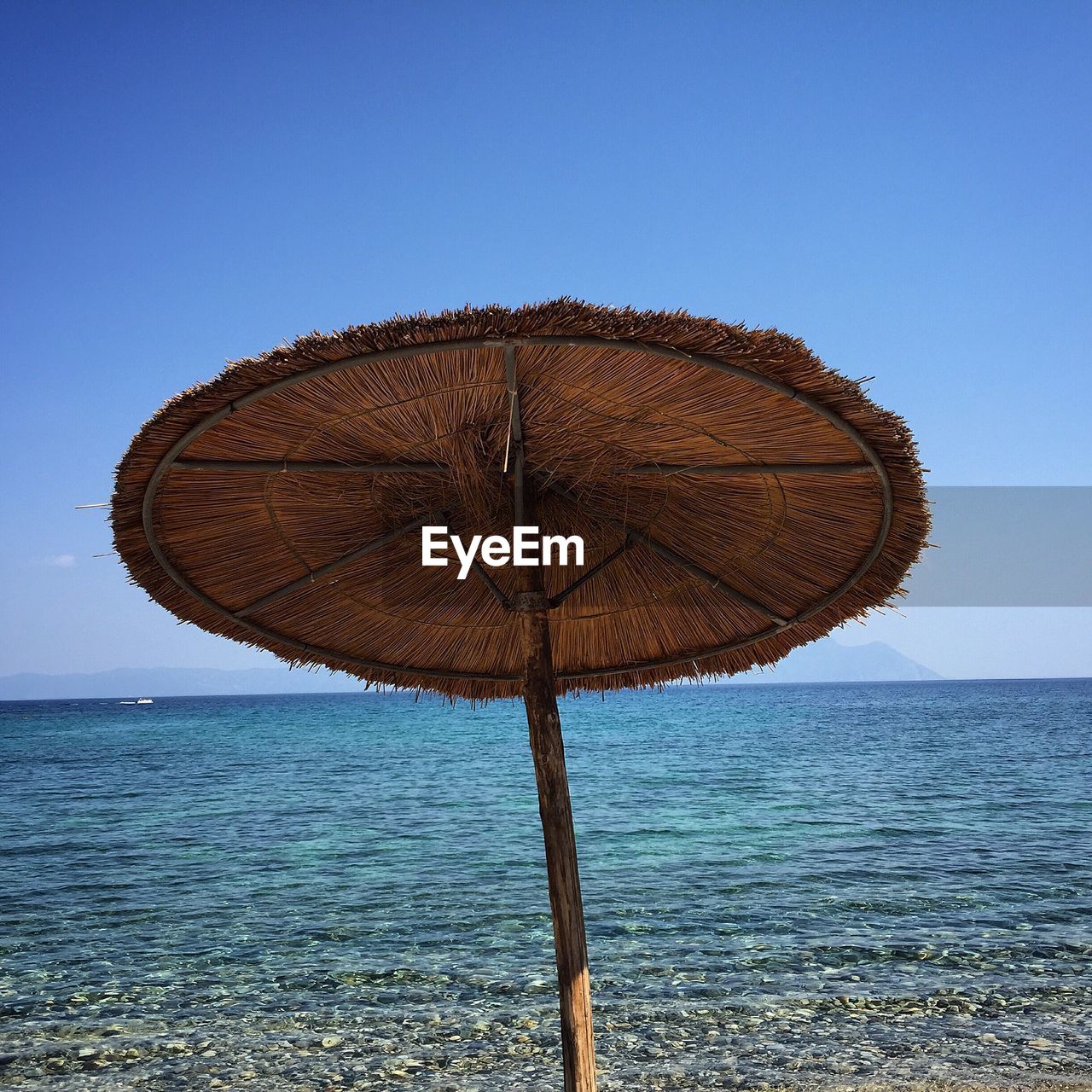 Parasol at beach against clear blue sky