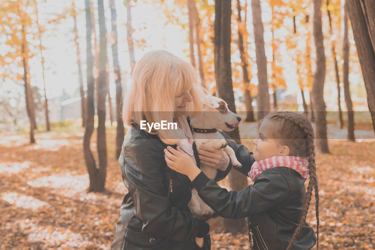 REAR VIEW OF MOTHER AND DAUGHTER IN AUTUMN TREES