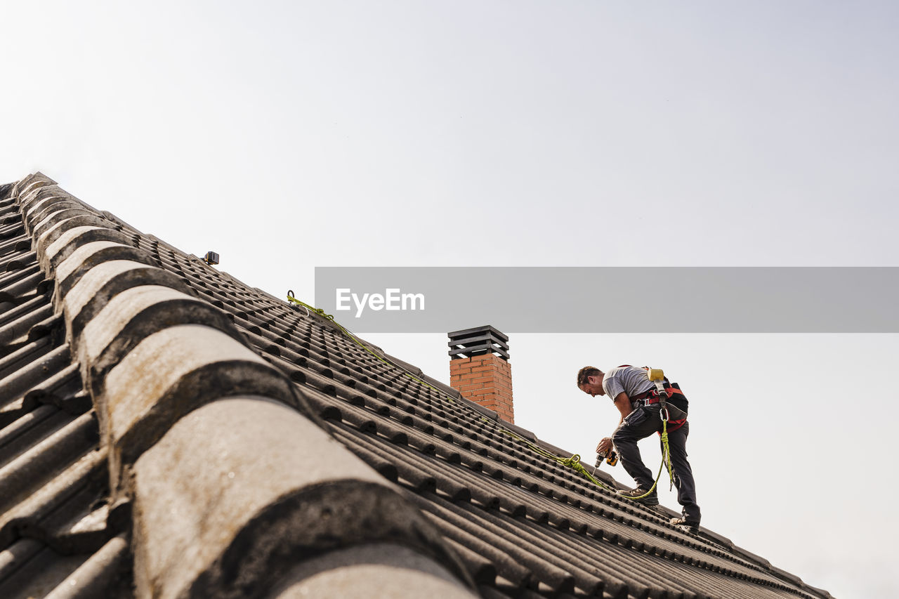 Technician using power tool on rooftop