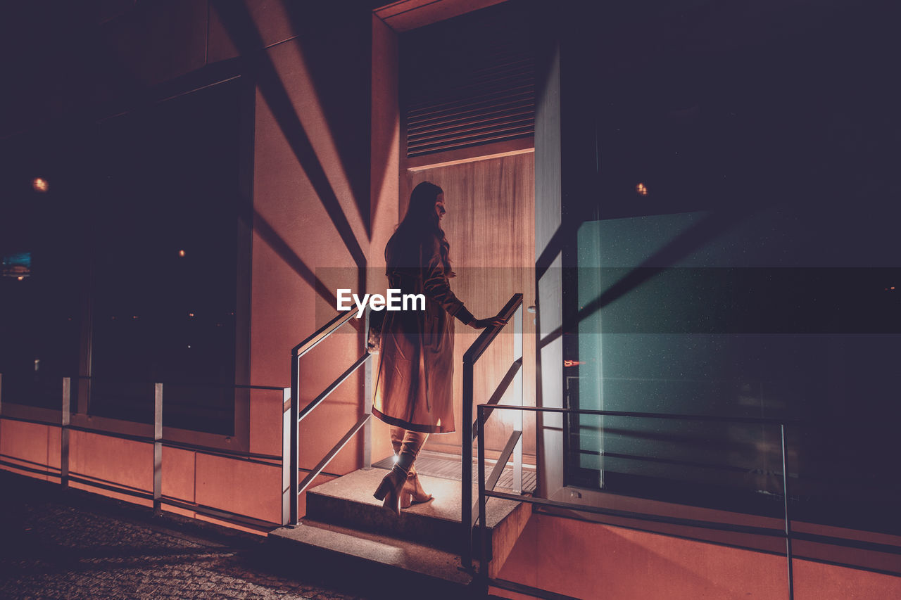 Woman standing on steps at entrance of building