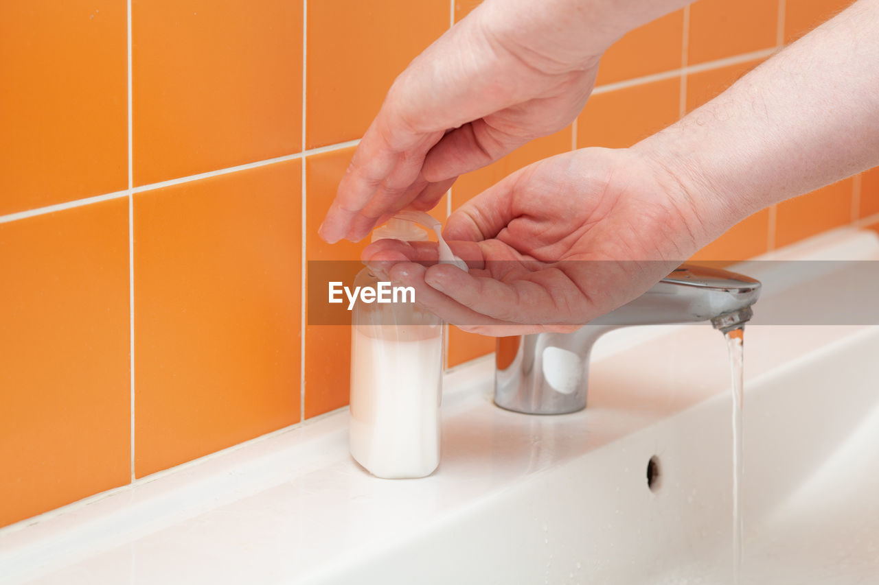 Close-up of hands using soap dispenser