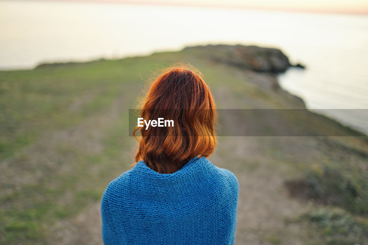 REAR VIEW OF WOMAN LOOKING AT SEA