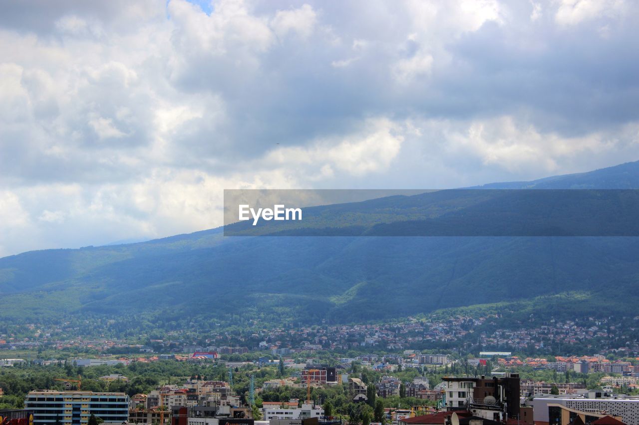 HIGH ANGLE VIEW OF TOWN AGAINST CLOUDY SKY