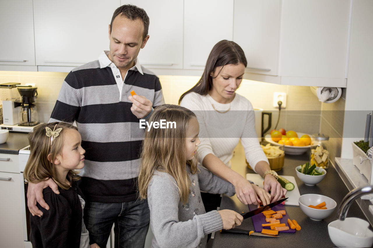 Family cutting vegetables at kitchen counter